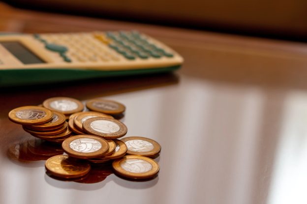 Consórcio vale a pena: moedas e calculadora representando planejamento financeiro sem juros